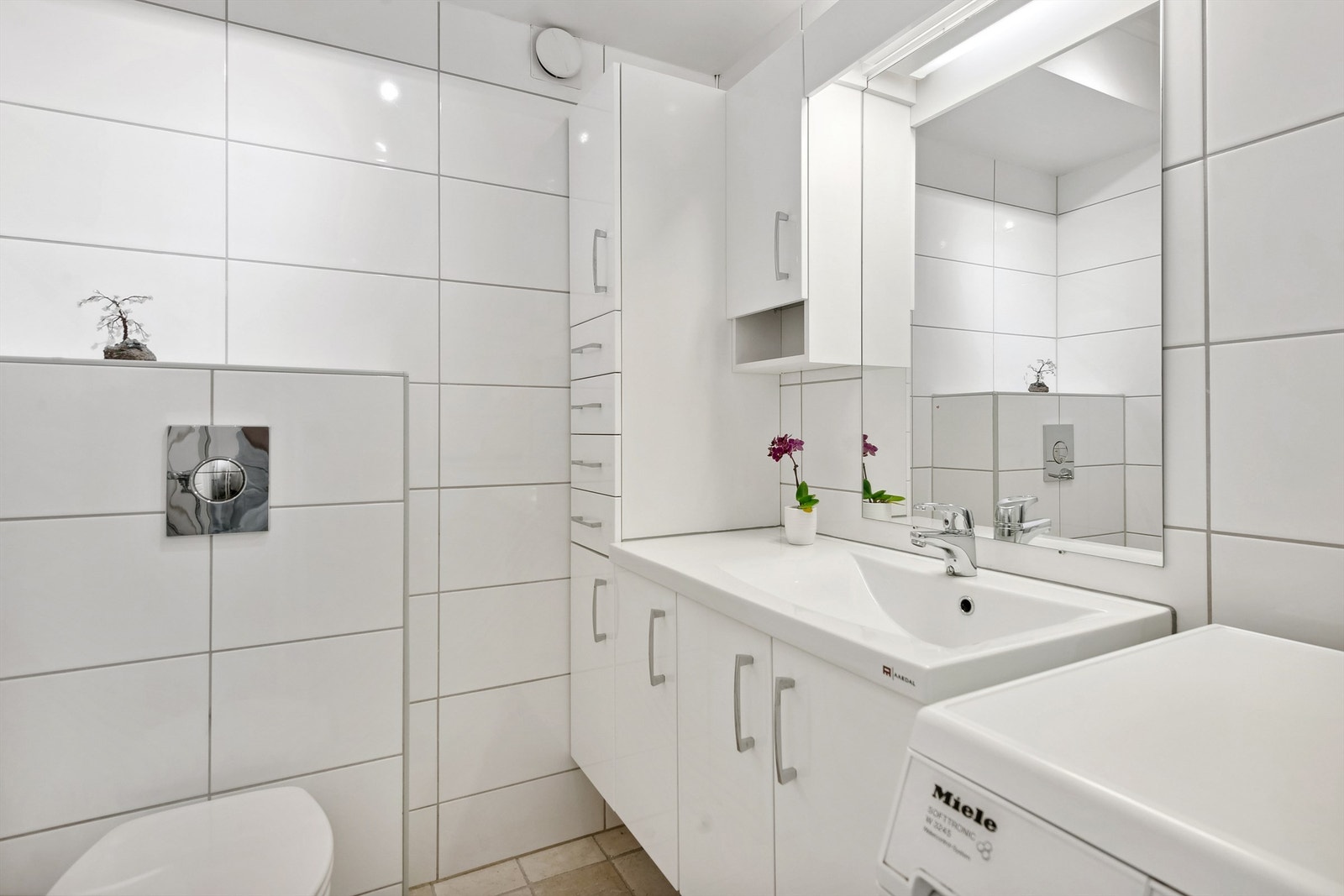 Badet er innredet med romslig vegghengt servantinnredning, speilskap med lys, veggmontert toalett Galleribilde