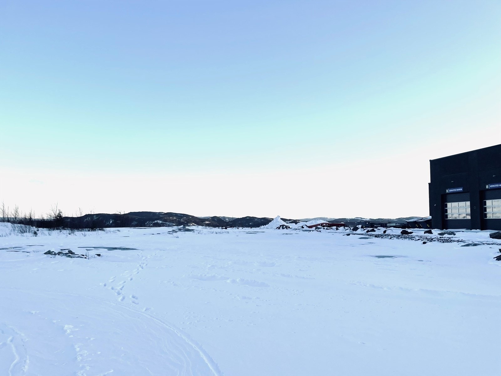 Tomt er flat med sprengstein og grus. Nabotomten til Hesselberg Maskin. Galleribilde