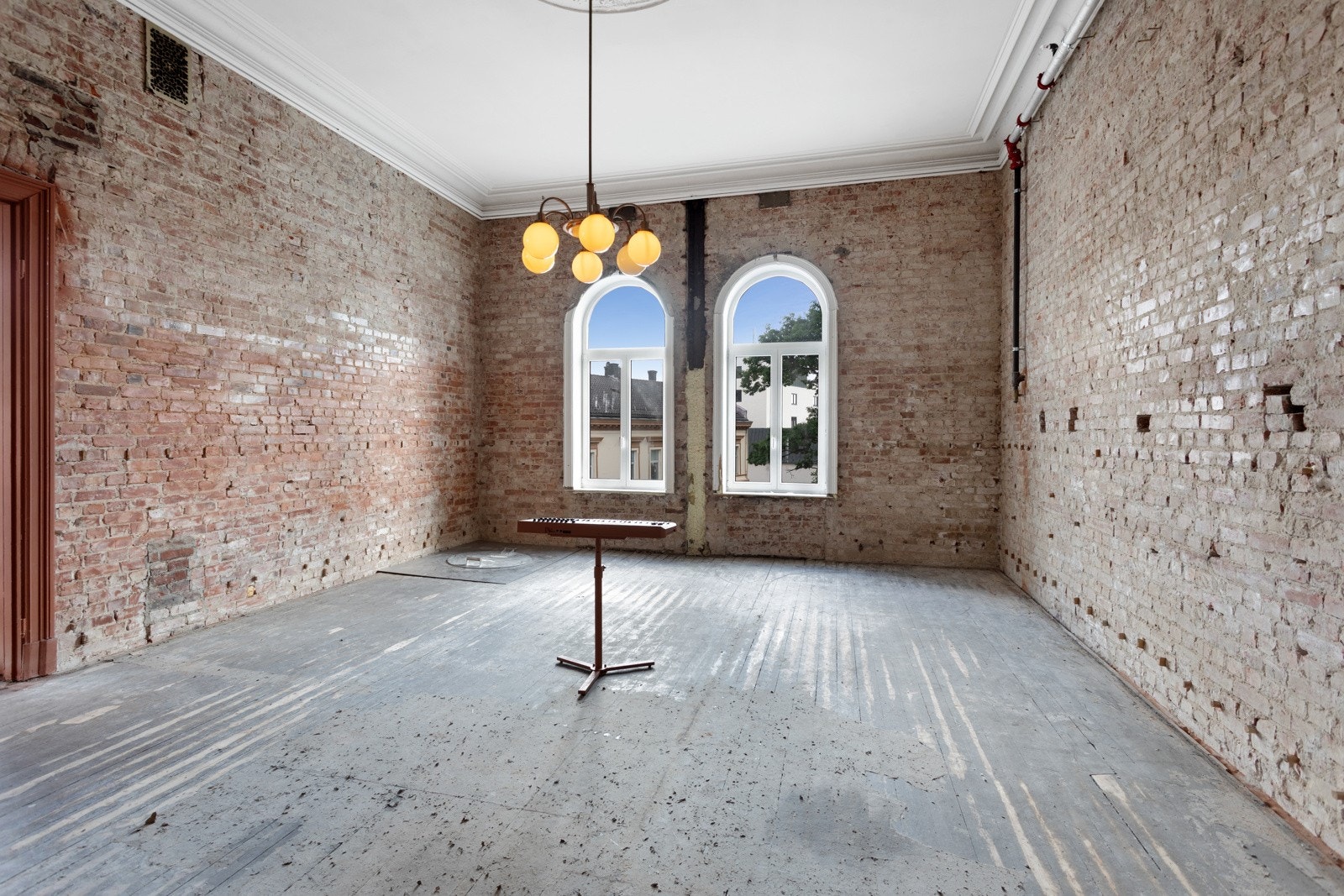 Et av rommene har naken tegl på alle vegger, røft, halvslipt gulv, stukkatur, takrosett og dagslys fra to buevinduer. Galleribilde