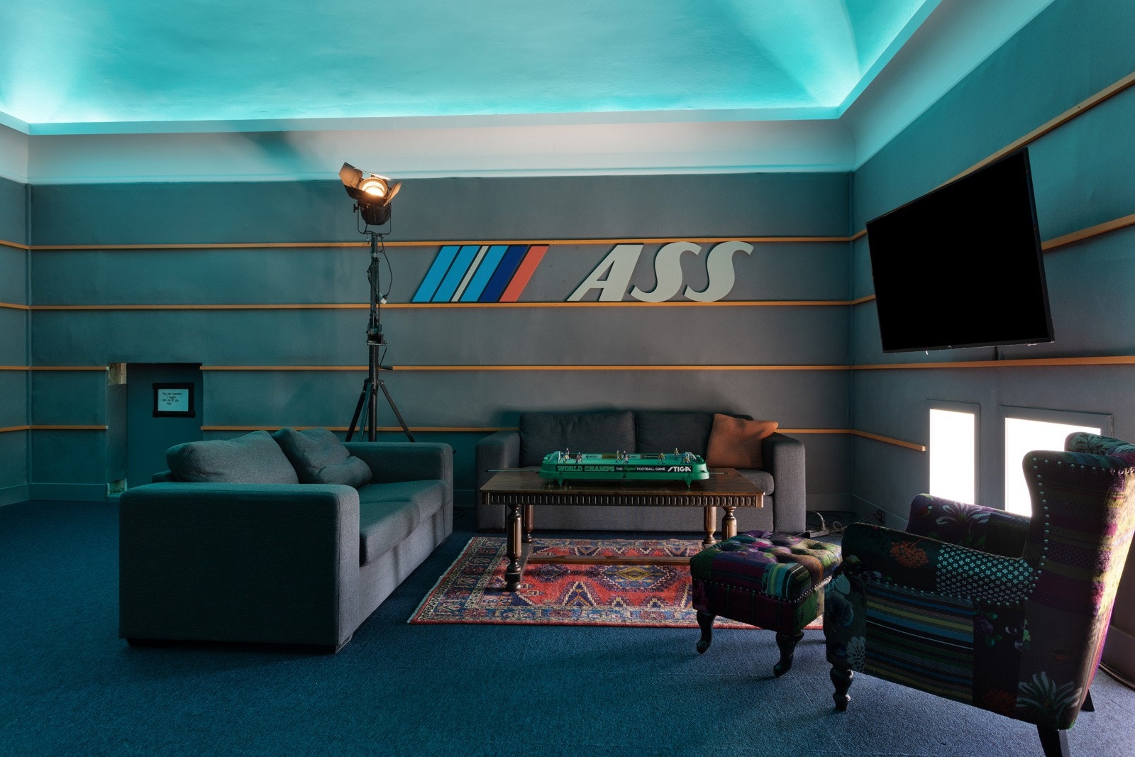 Rommet har små vinduer i kneveggene, teppe på gulv og grå veggflater med horisontale lister. Galleribilde