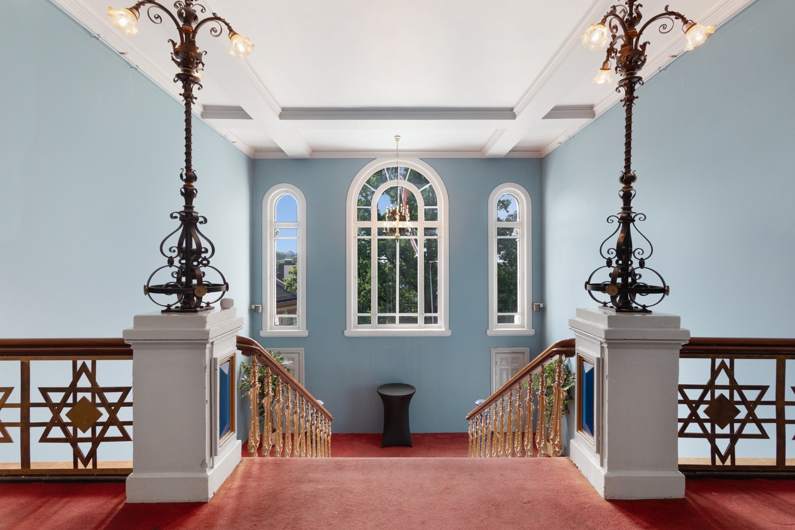 Trappen er rikt utsmykket i form av nydelige balustre, massive meglere og utsøkte lamper i smijern plassert på hver stolpe øverst før inngangen til storsalen. Trapperommet får dagslys fra buede vinduer på midterste plan, mellom andre og tredje etasje. Galleribilde