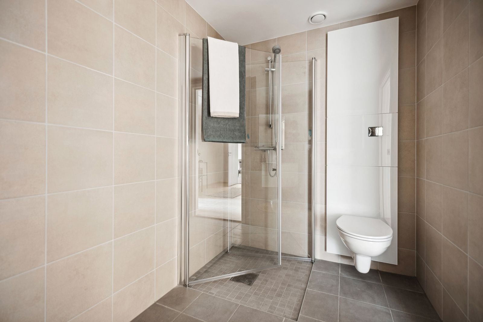 Flislagt baderom med dusjhjørne og innbygd toalett. Bilder fra leil. E101. Galleribilde