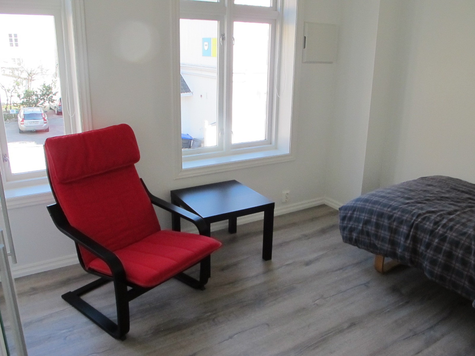 En stol og et lite bord hører med. Det er to store vinduer i dette rommet. Galleribilde