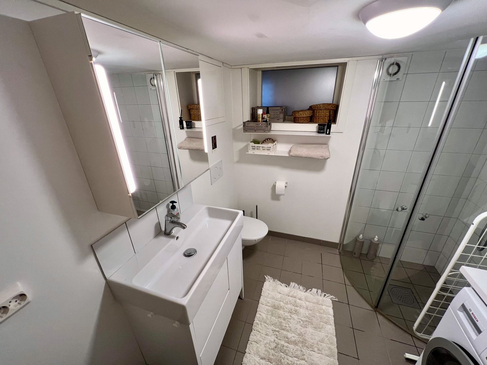 Bad med dusjhjørne og vaskemaskin med inkludert tørketrommel Galleribilde