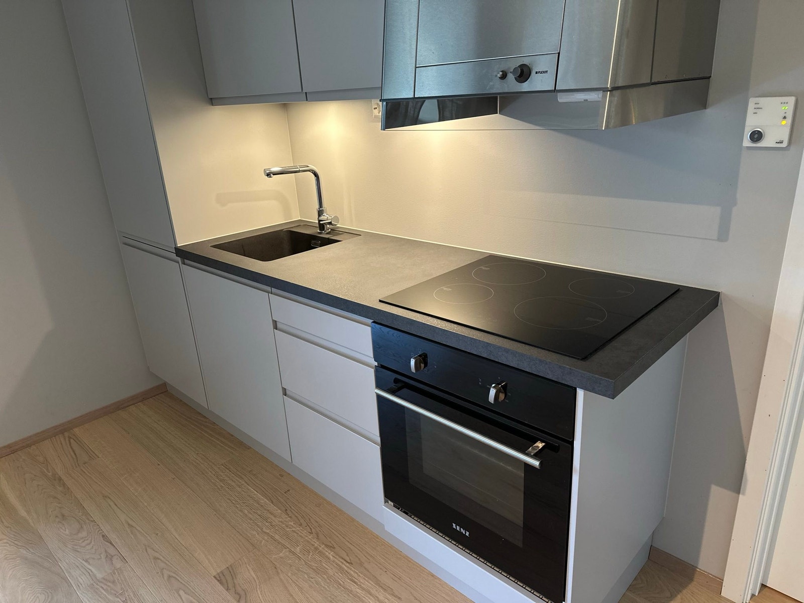 Kjøkken utstyrt med koketopp, vask, stekeovn, avtrekksvifte, kjøleskap og fryser Galleribilde