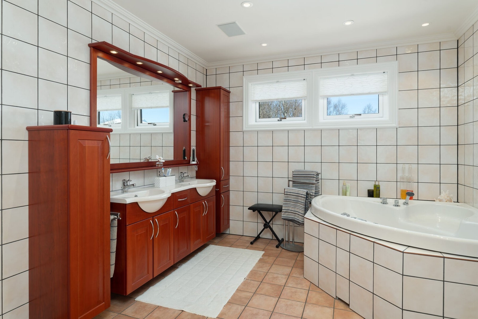 Badet har veggmontert toalett, bidet, badekar, dusj og dobbel servant på innredning med god lagringsplass. Galleribilde