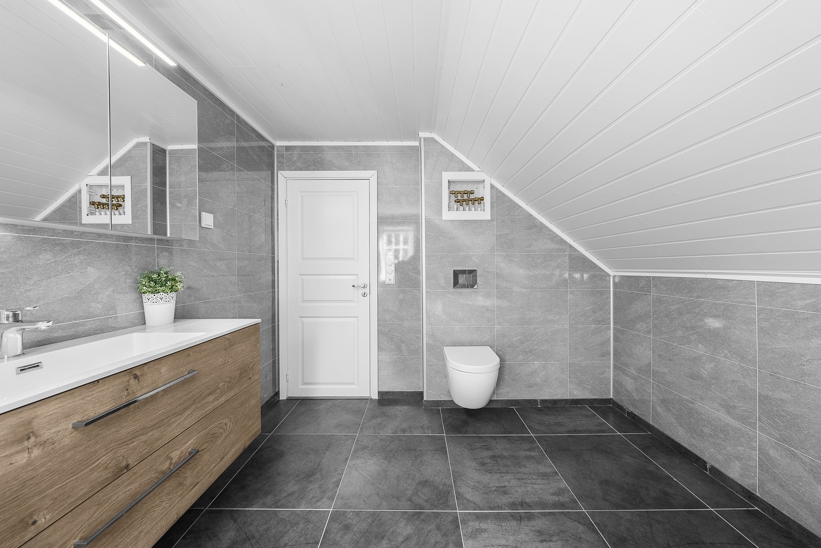 Vegghengt toalett, hjørnebadekar og varmekabler i gulv. Galleribilde