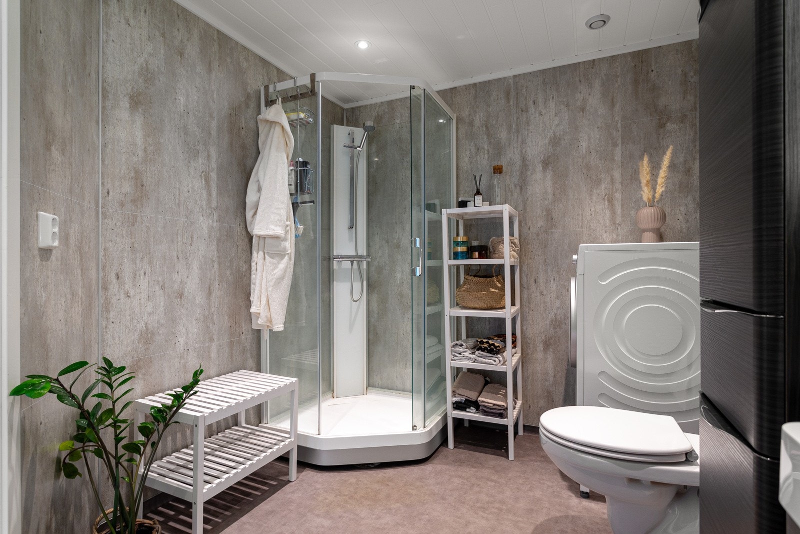 Moderne bad utstyrt med vegghengt toalett, dusjkabinett og servantinnredning med speil, samt opplegg for vaskemaskin. Galleribilde