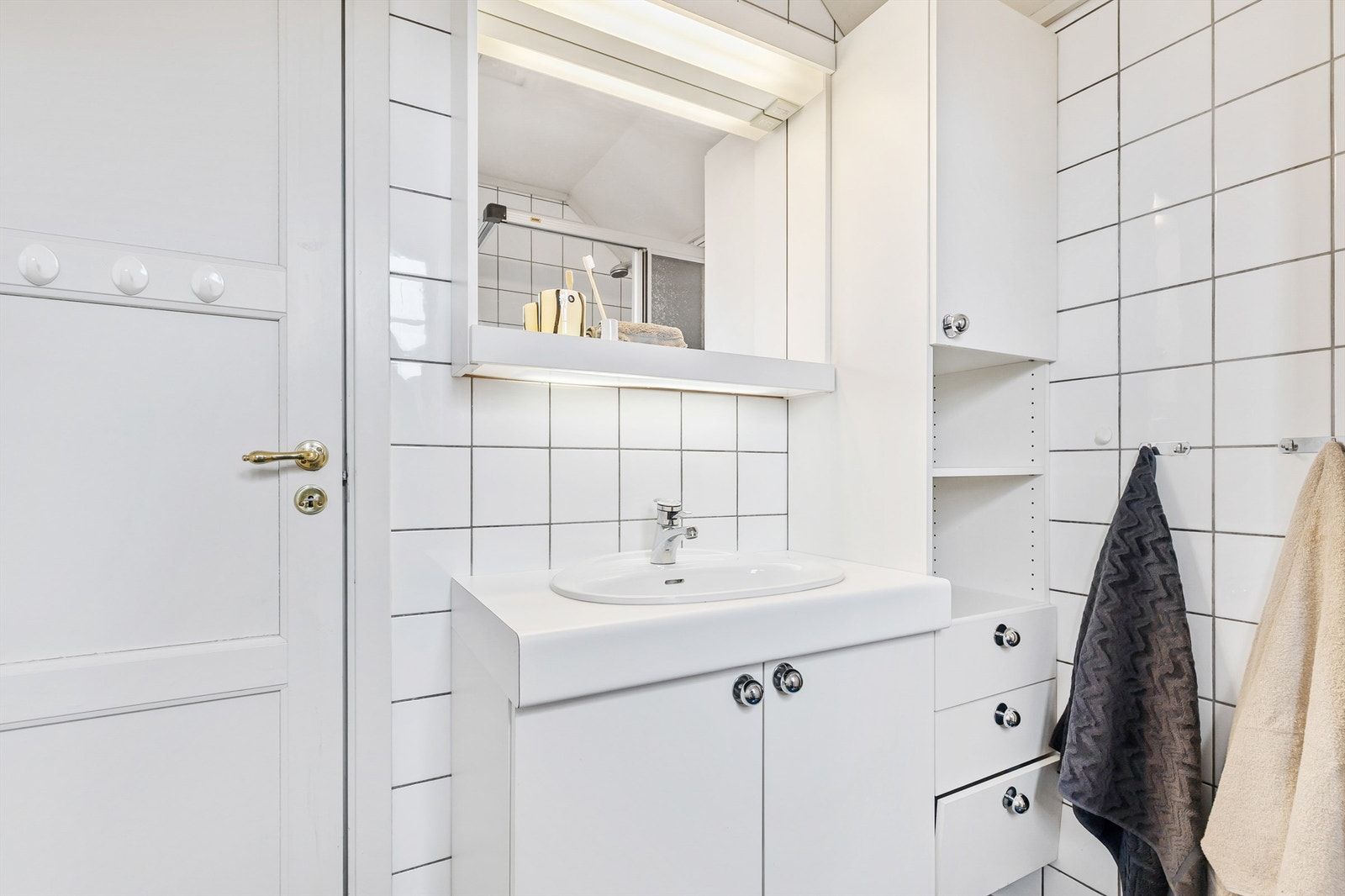 Badet er innredet med gulvstående toalett, vegghengt servantskap og dusjhjørne med skyvedører. Galleribilde