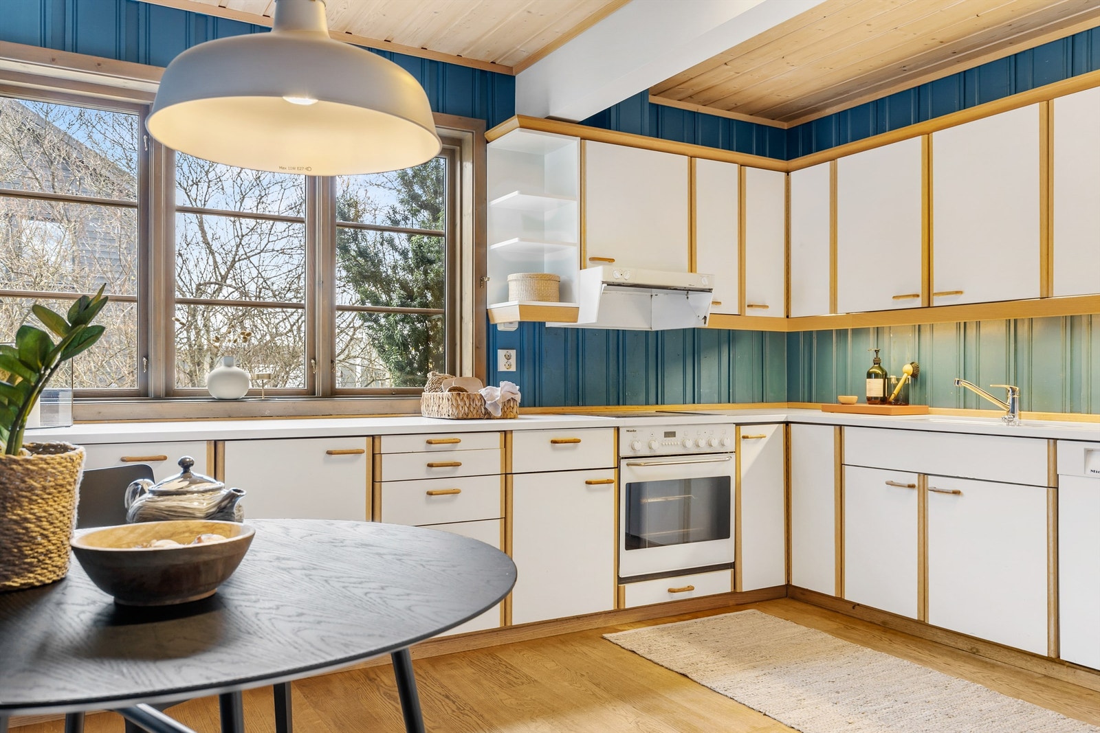 Kjøkkenfronter med glatt overflate med omramming med eik/eikefiner. Benkeplate av kompositt med nedfelt oppvaskkum. Galleribilde