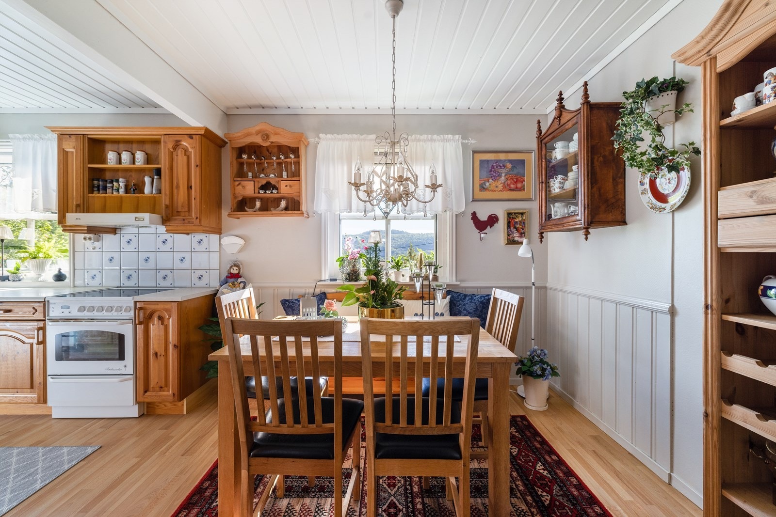 Lyst og hyggelig kjøkken av god størrelse, med fin spiseplass ved det ene kjøkkenvinduet og velholdt kjøkkeninnredning av furu fra byggeår. Galleribilde