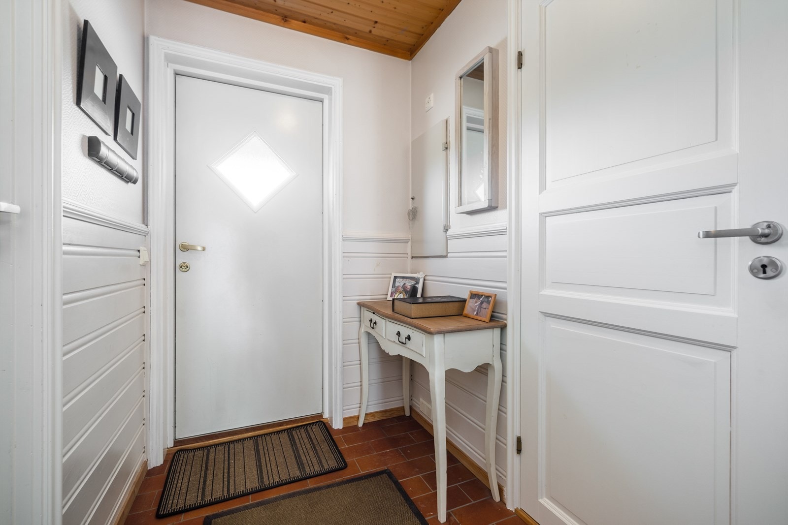 Hyggelig og lys entré med praktisk tilliggende vaskerom og toalettrom. Her er også boenhetens sikringsskap plassert, med automatsikringer fra byggeår. Galleribilde