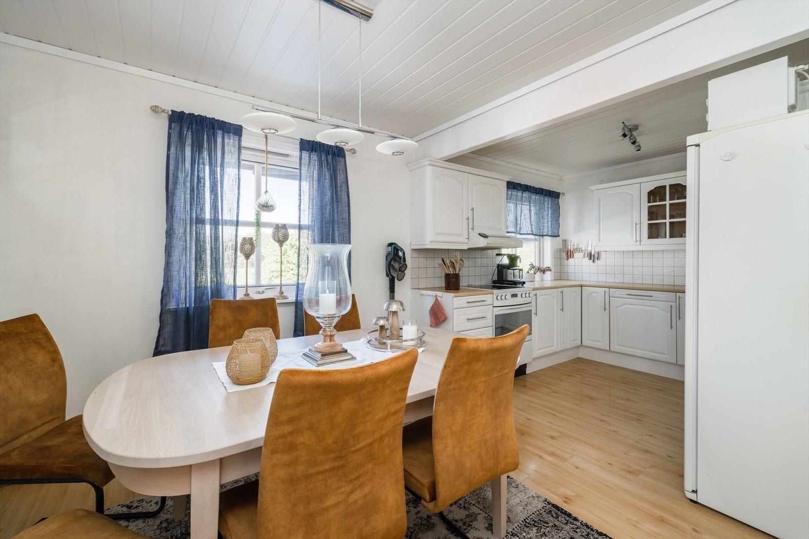 Spisestuen finner sin naturlig plassering ved kjøkkenet som ligger i delvis åpen løsning. Kjøkkenet har velholdt kjøkkeninnredning fra byggeår. Galleribilde