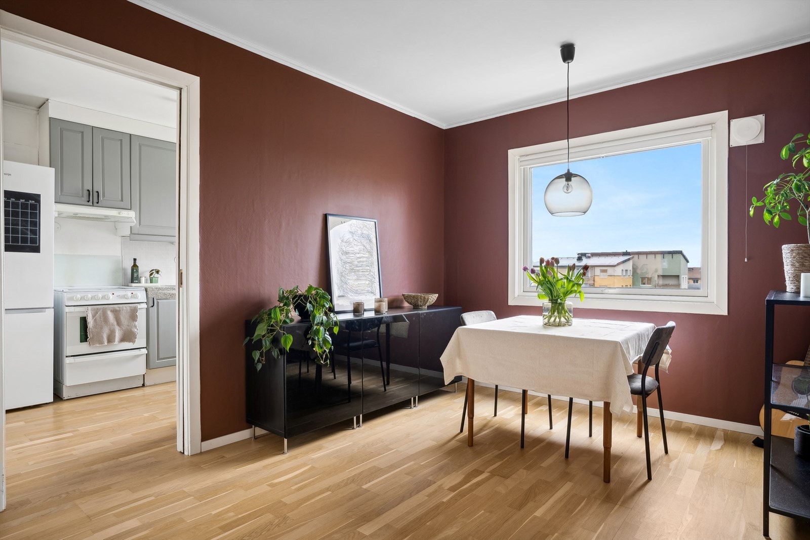 Stor spiseplass med moderne fargevalg på vegger og stort vindu i nærhet av kjøkken Galleribilde