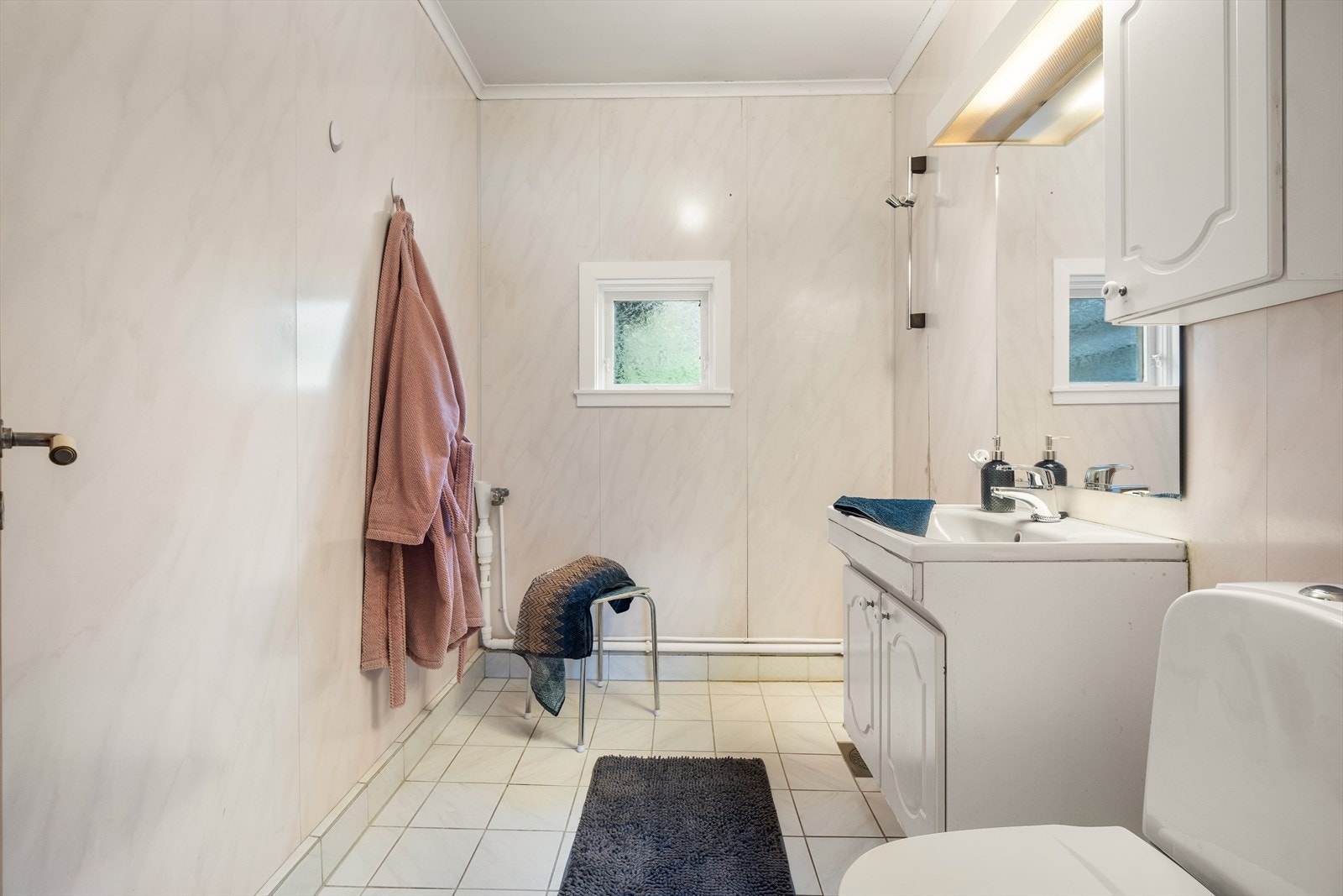 Badet har flislagt gulv og baderomsplater på vegger. Galleribilde