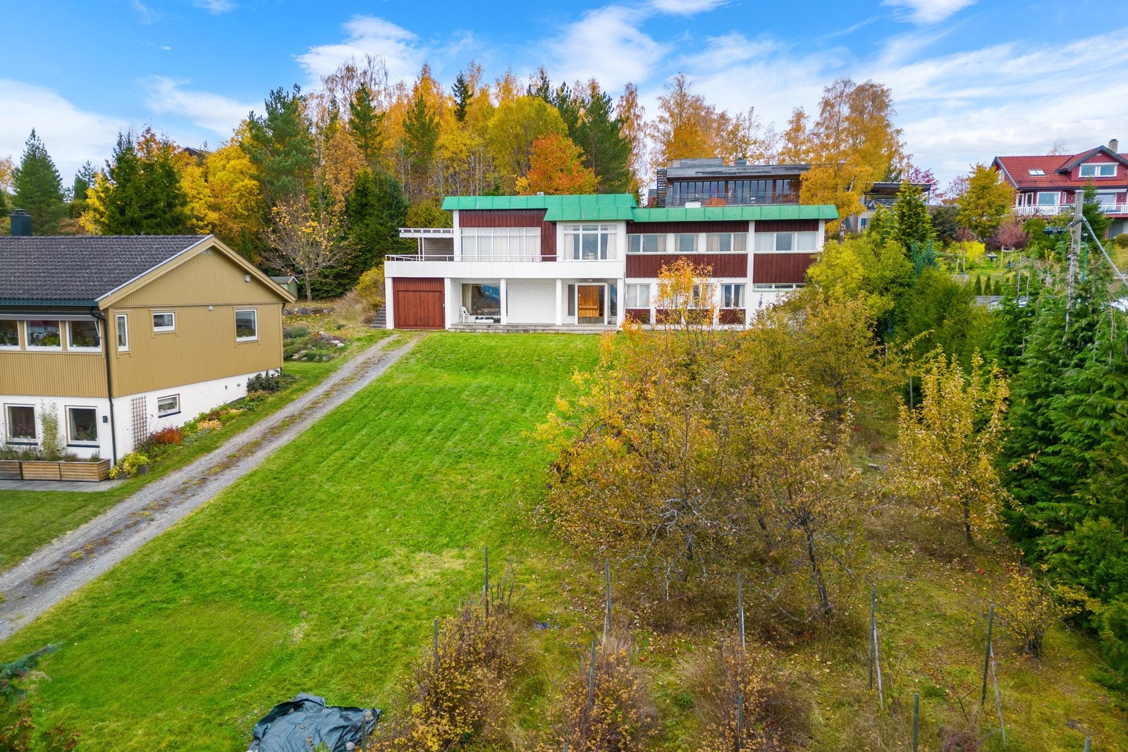 Mellom veien og boligen er det opparbeidet store grøntarealer med diverse beplantning med busker og frukttrær. Galleribilde