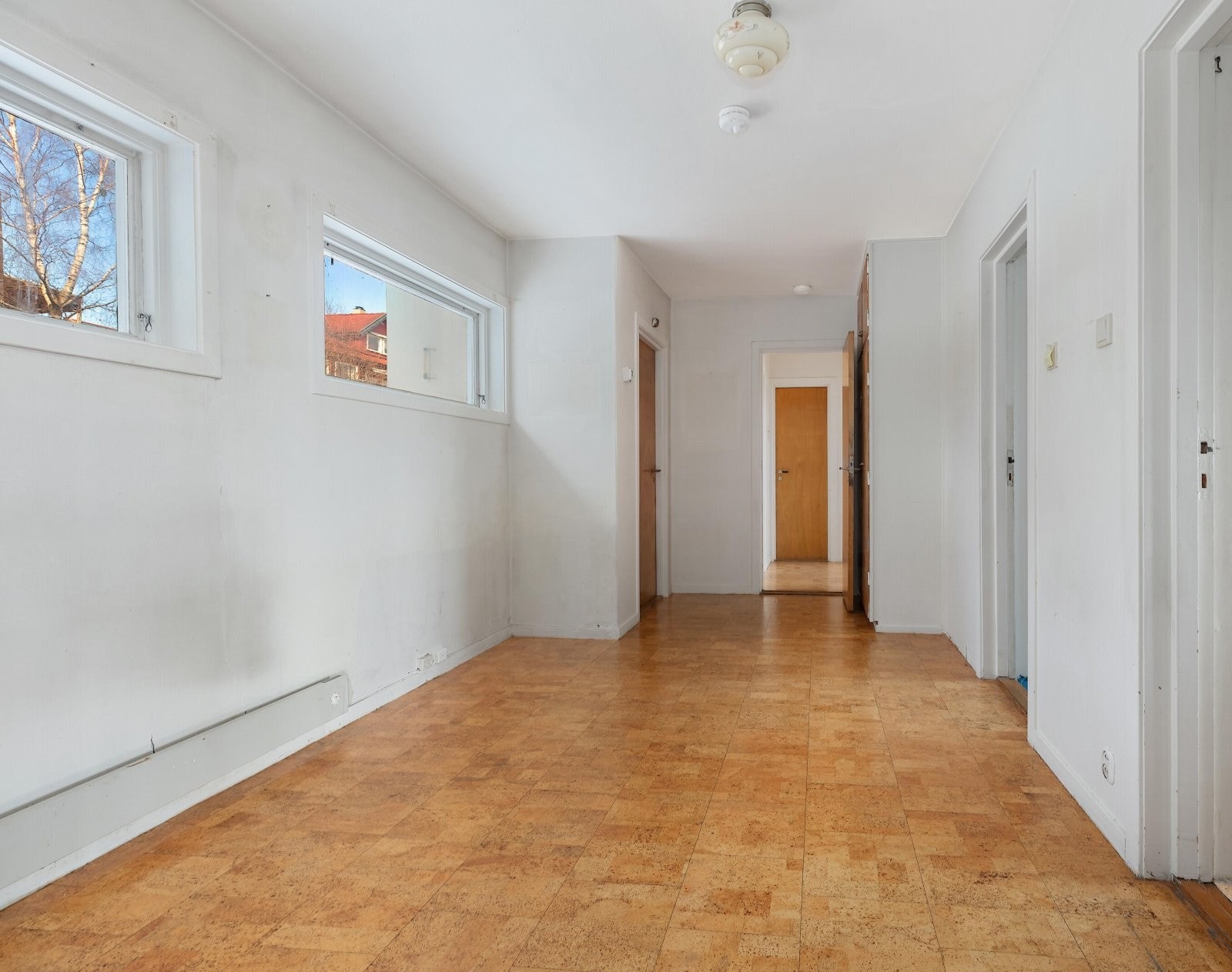 Stort allrom/lekerom med utgang til husets bakside hvor det er opparbeidet med plen og busker Galleribilde