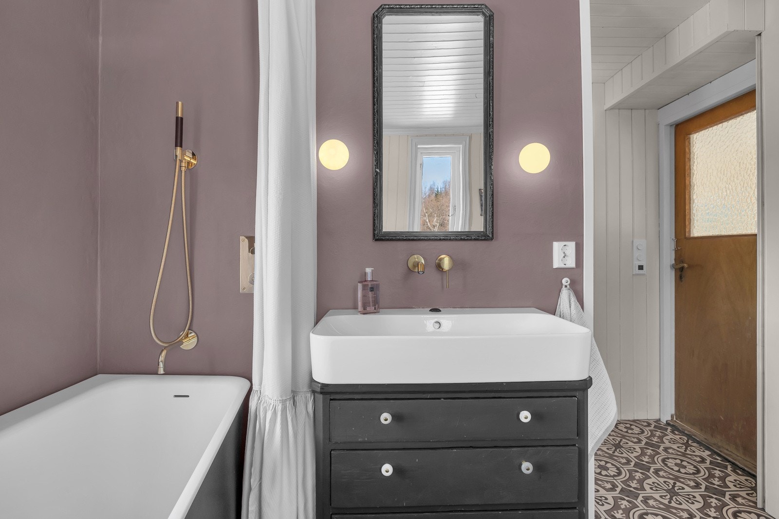 Her er det flotte fliser på gulv, lekkert garnityr, baderkar og opplegg for vaskemaskin og tørketrommel Galleribilde