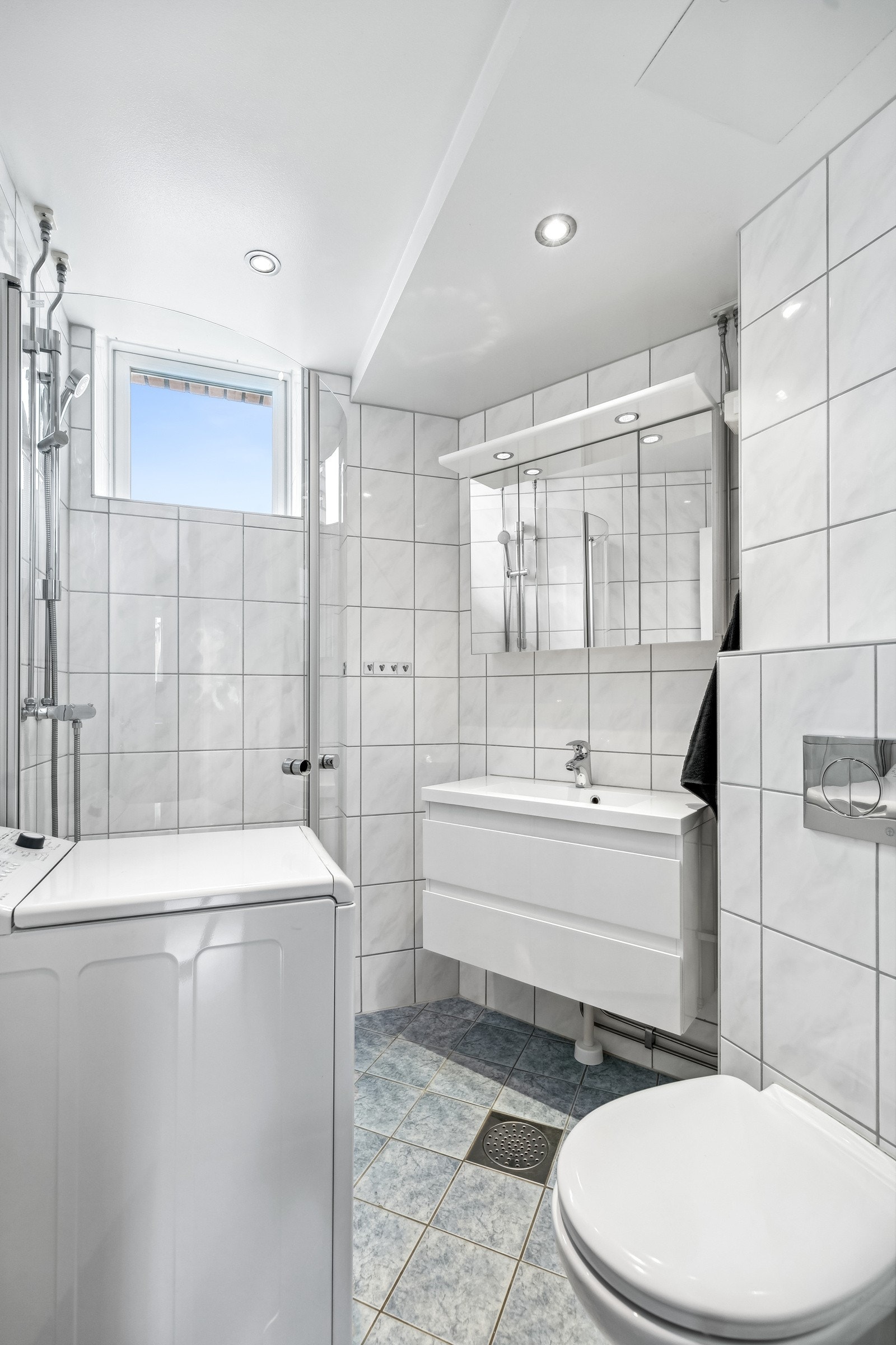 Badet har dusjhjørne med innsvingbare dører, vegghengt toalett og opplegg for vaskemaskin. Galleribilde