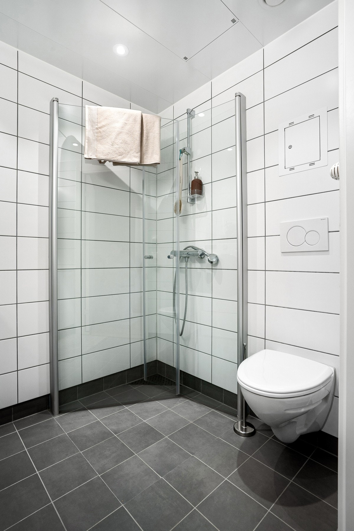 Badet er utstyrt med dusjhjørne med praktisk innfellbare glassdører og vegghengt toalett for enklere rengjøring. Galleribilde