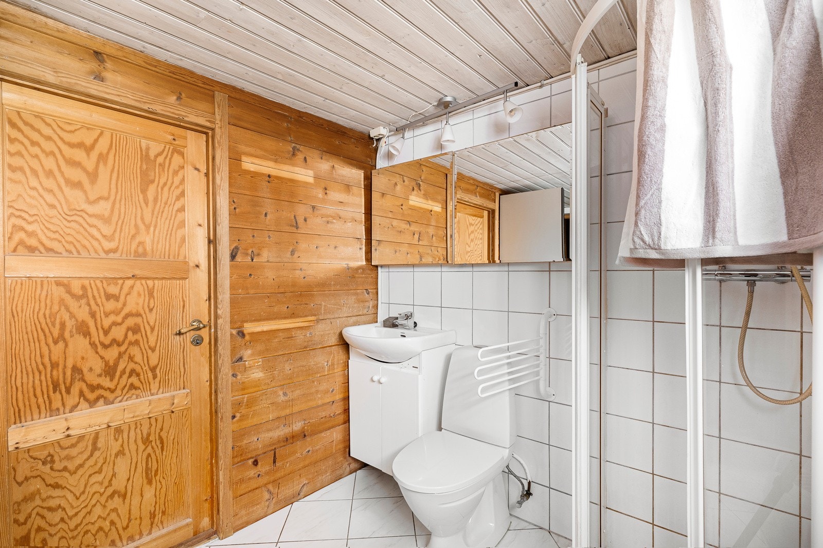 Bad/vaskerom i kjelleren med hvite fliser på gulv og gulvvarme. Galleribilde