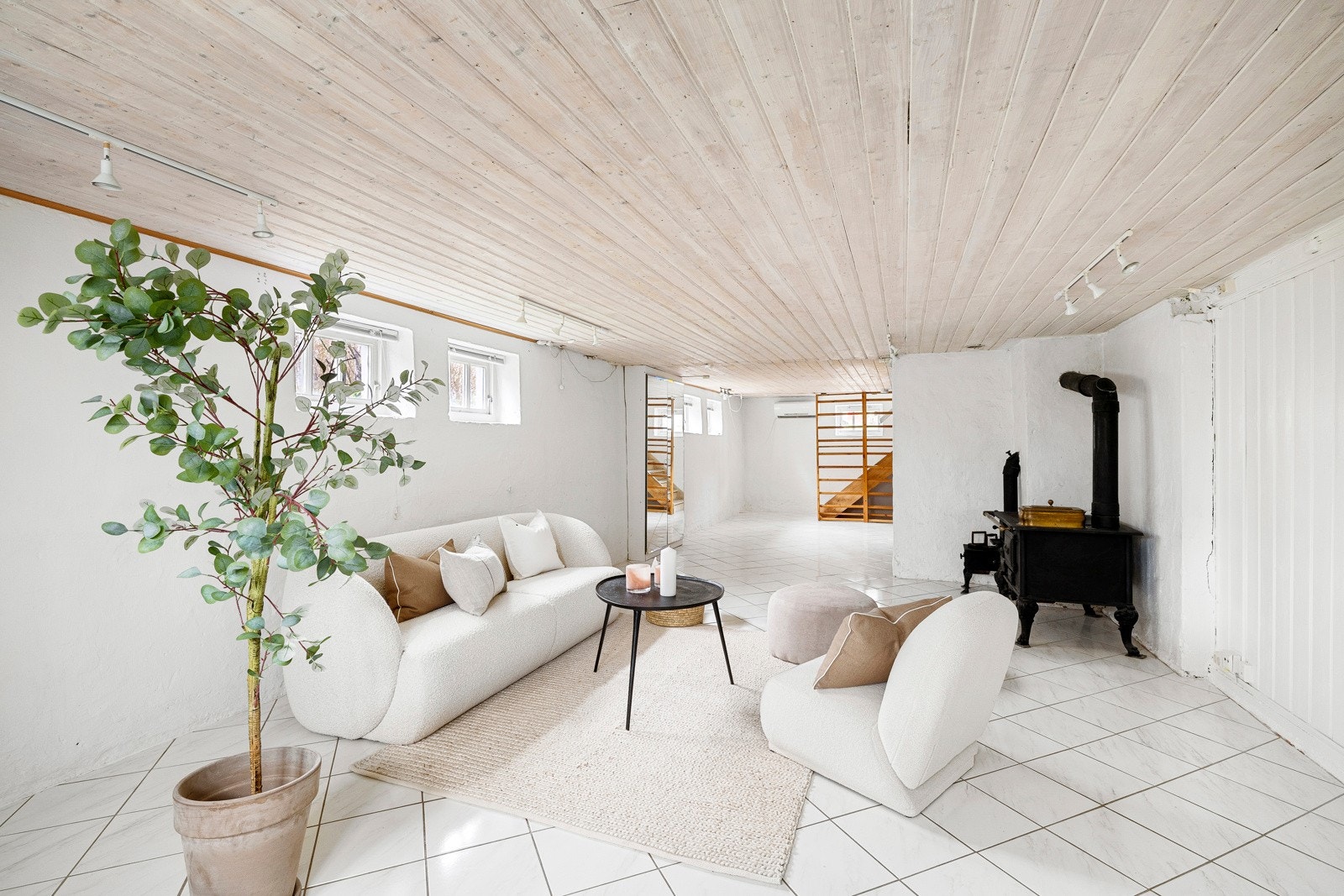 Kjellerstuen har hvitmalte vegger, og det er hvite fliser på gulv med gulvvarme. Galleribilde