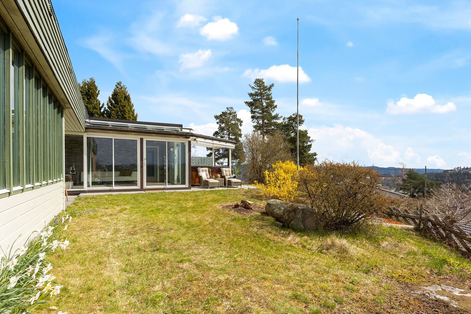 Tomten er rikt beplantet med ulike prydbusker, prydtrær og blomsterbed samt naturlig vegetasjon som utgjør en flott og idyllisk ramme rundt boligen Galleribilde