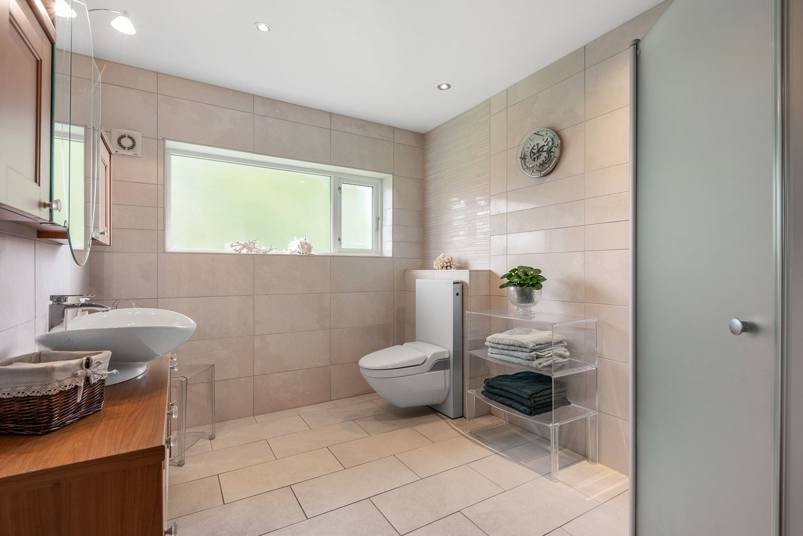 Baderommet har fliser på vegger og gulv, med varmekabler Galleribilde