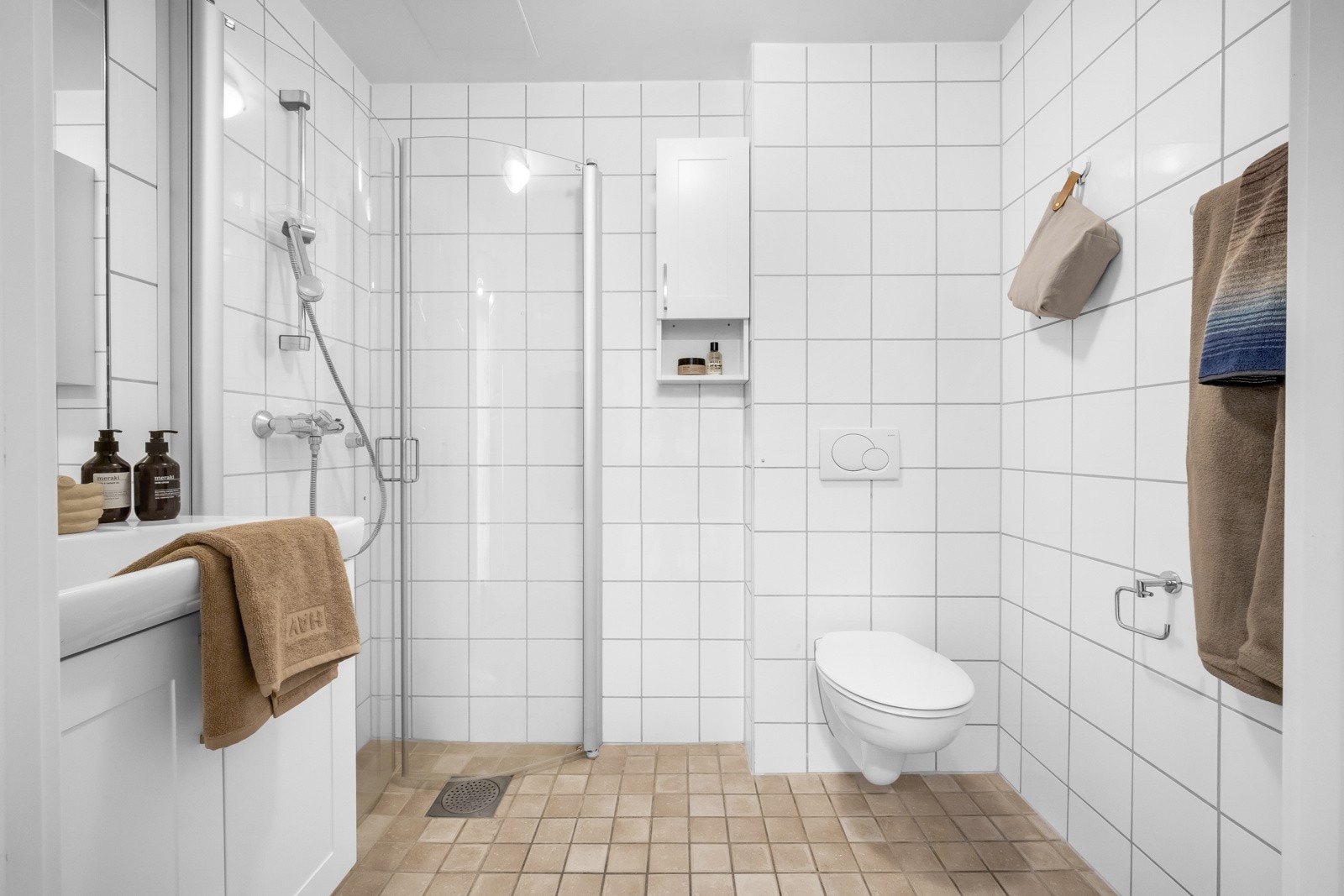 Baderom innredet med dusjnisje, servant med servantskap og vegghent klosett. Galleribilde