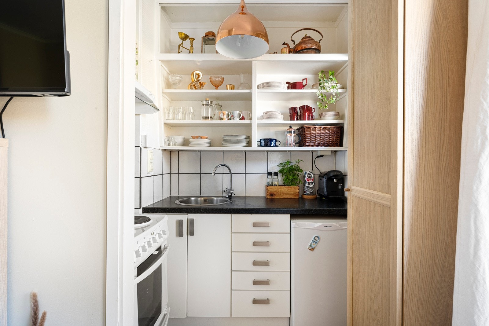 Kjøkkenet ligger tilbaketrukket fra stuen og har hvit innredning. Galleribilde