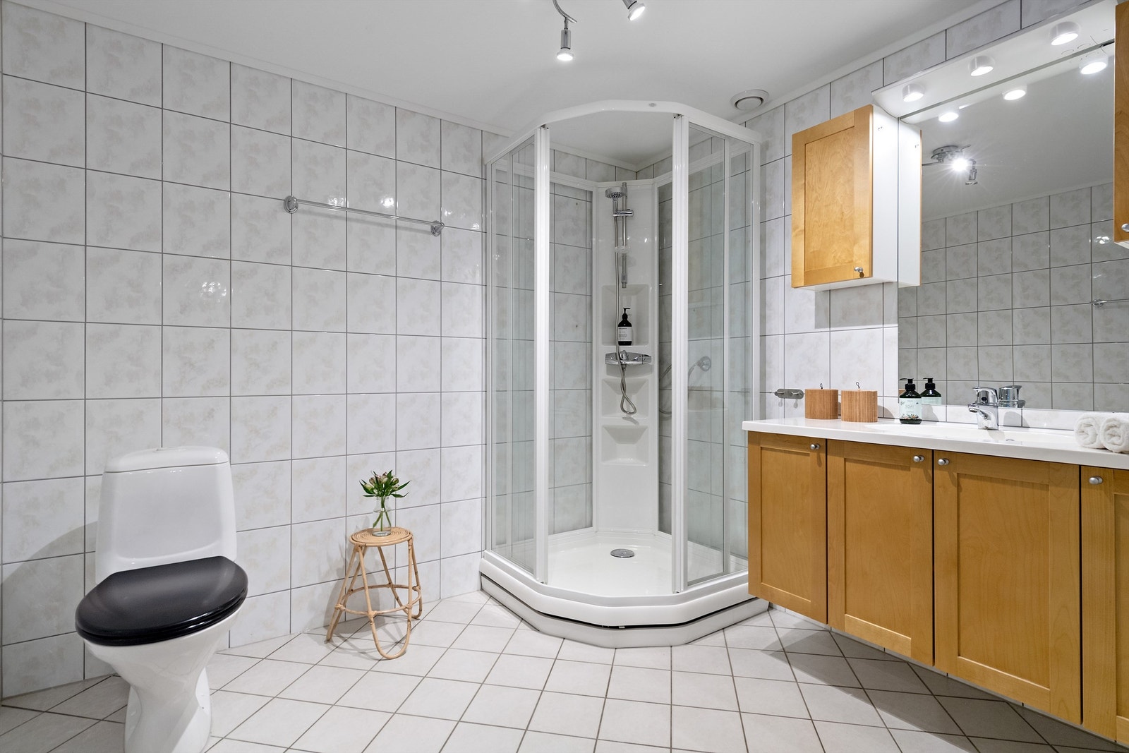 Flislagt bad med wc, dusjkabinett og innredning med profilerte fronter i heltre og heldekkende servantplate. Galleribilde