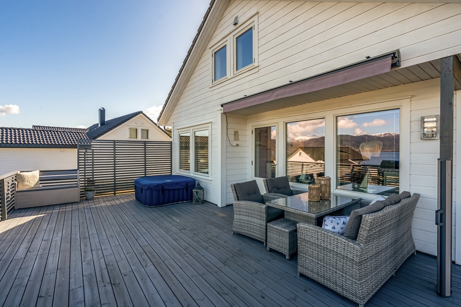 Utgang til romslig terrasse med motorisert markise, utdragbar skillevegg for ly mot vind og nydelig fjordutsikt. Galleribilde