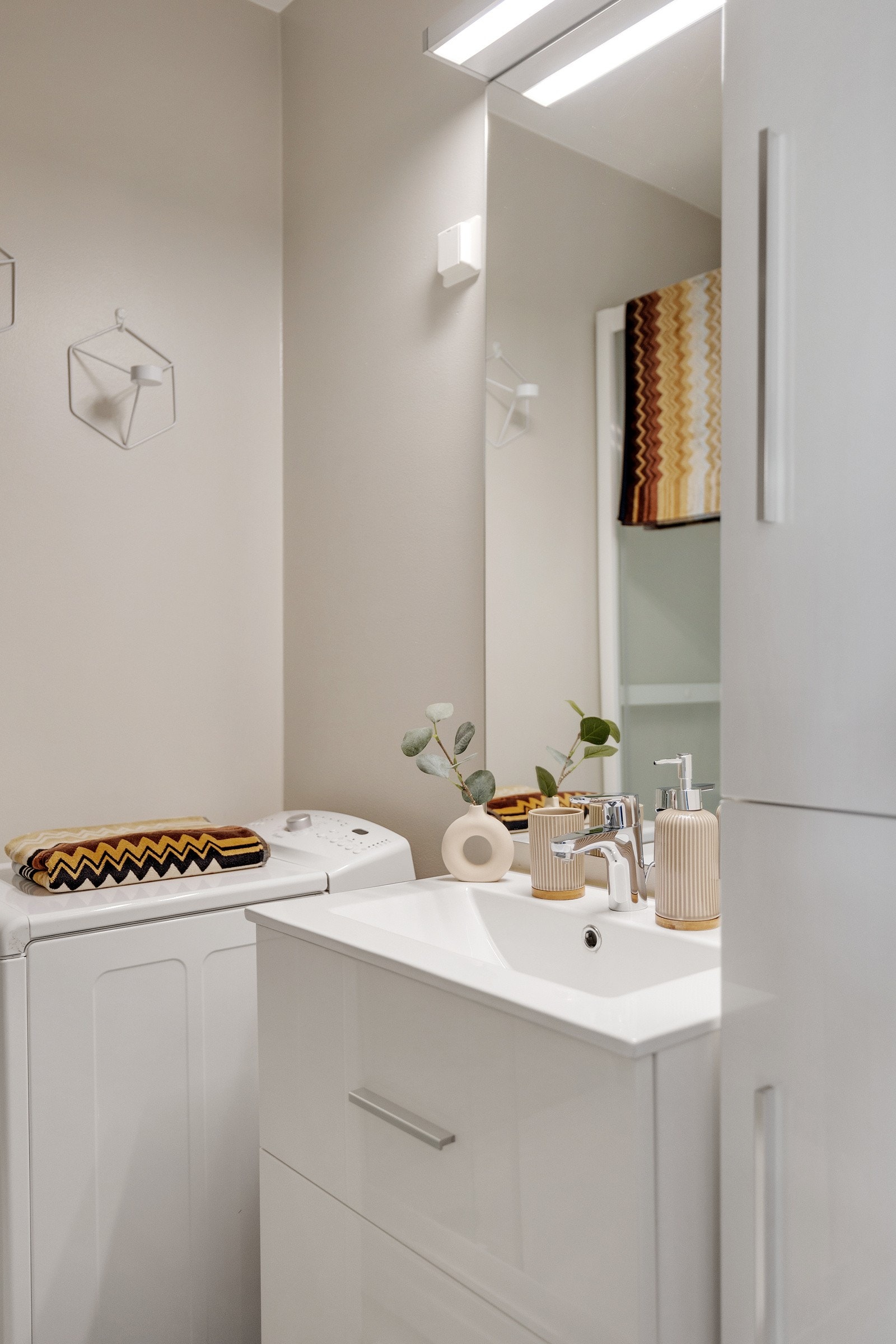 Rommet er innredet med dusjkabinett, servant med skuffeinnredning, frittstående toalett og opplegg for vaskemaskin. Galleribilde