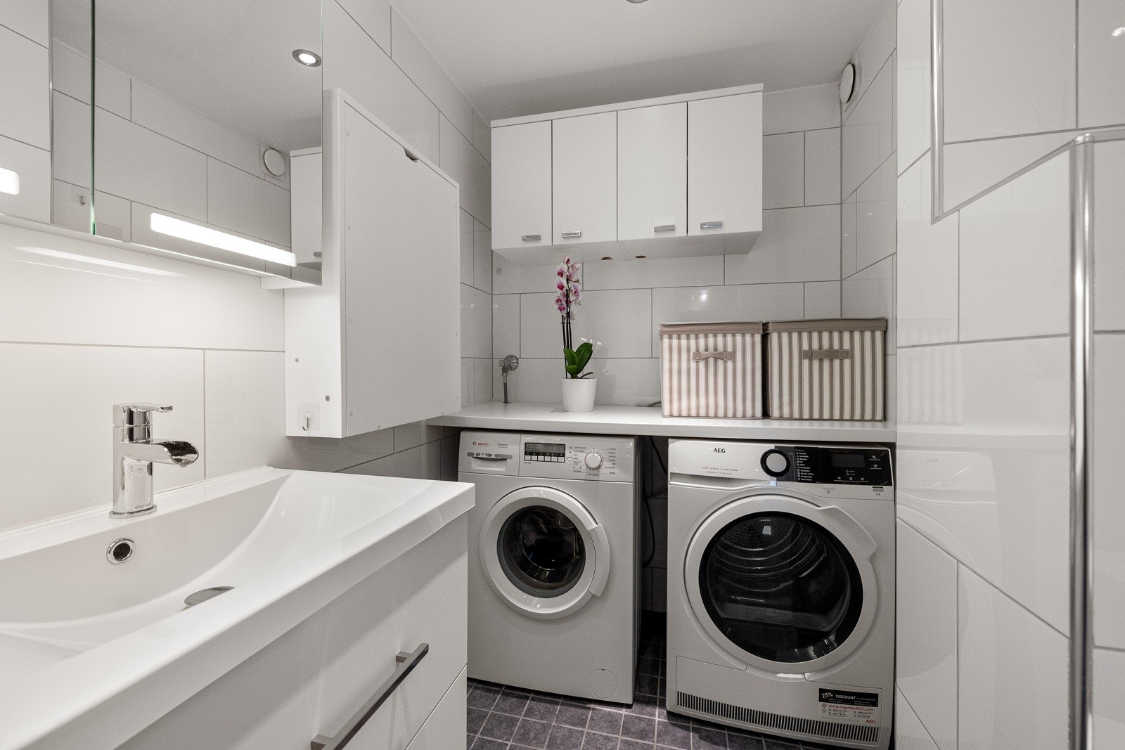 Badet har en praktisk og funksjonell vaskeavdeling med opplegg til vaskemaskin og tørketrommel under benk, samt oppbevaringsplass i overskap. Galleribilde