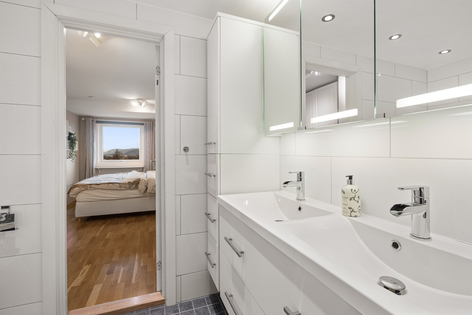 Badet har rikelig med oppbevaringsplass i høyskap, servantskap og speilskap med belysning. Galleribilde