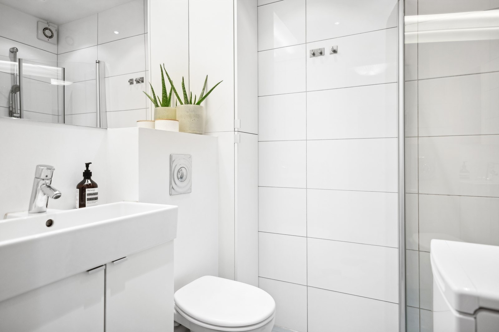 BaderomBad/wc består av vegghengt wc, servant m/underskap, speil m/overlys, veggskap, inn-/utadslående dusjdører og opplegg for vaskemaskin. Galleribilde