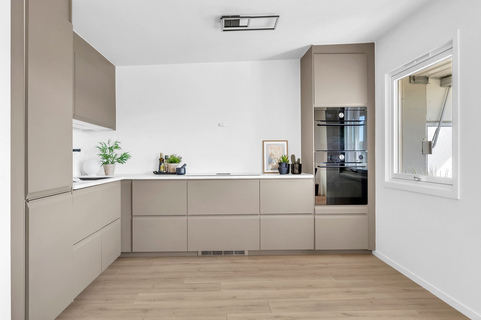 Lekkert og moderne kjøkken fra 2023 med integrerte hvitevarer som stekeovn, oppvaskmaskin, kjøleskap med fryser og platetopp med innebygd ventilator og komfyrvakt Galleribilde