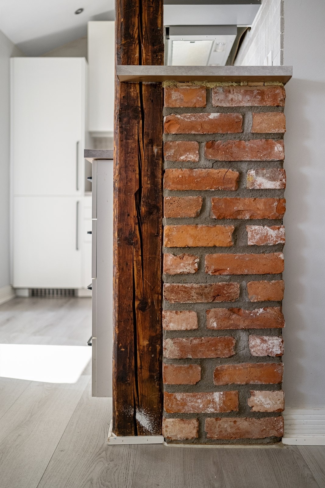 Loftsleiligheten er utsmykket med teglstein og synlige trebjelker. Galleribilde