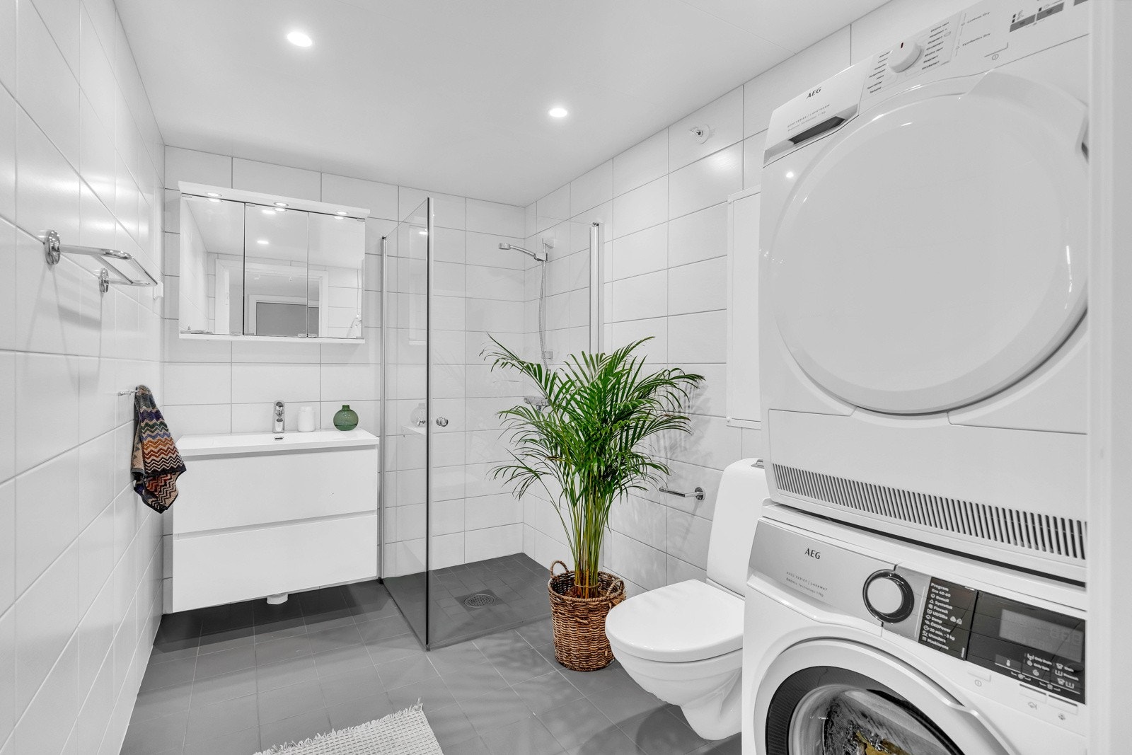 Badet er helfliset med varme i gulvet, downlights fra himling og opplegg for vaskemaskin Galleribilde