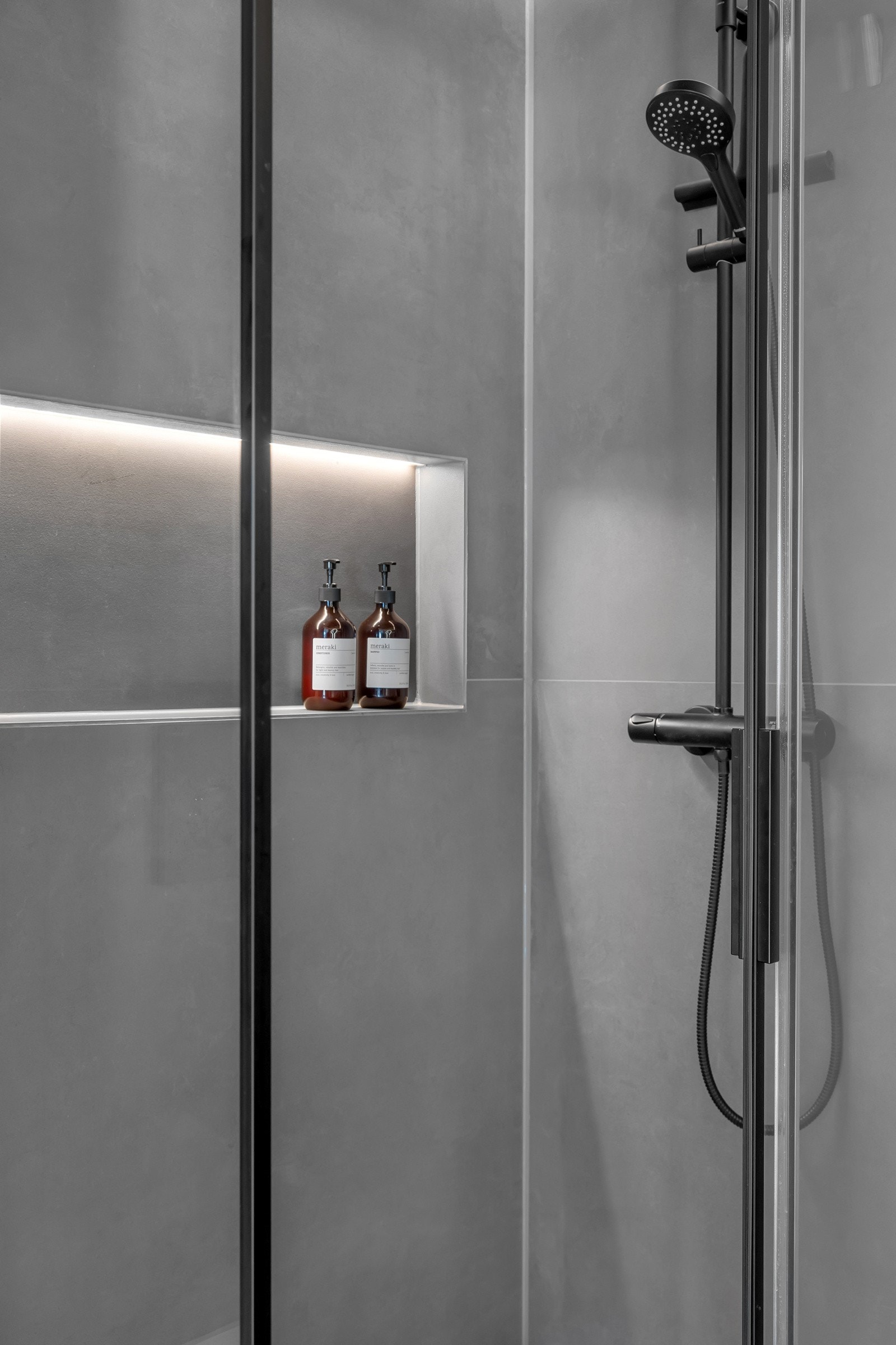 Fin dusj med tidsriktig garnityr og en praktisk innfelt hylle Galleribilde