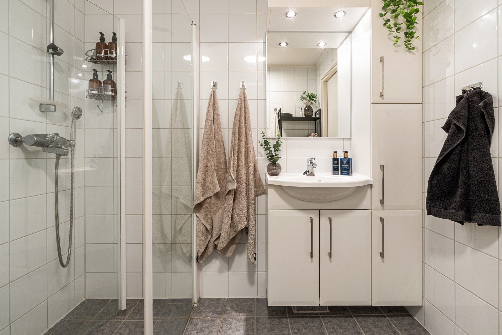 Lys baderomsinnredning med heldekkende servant, speil med lys og høyskap Galleribilde