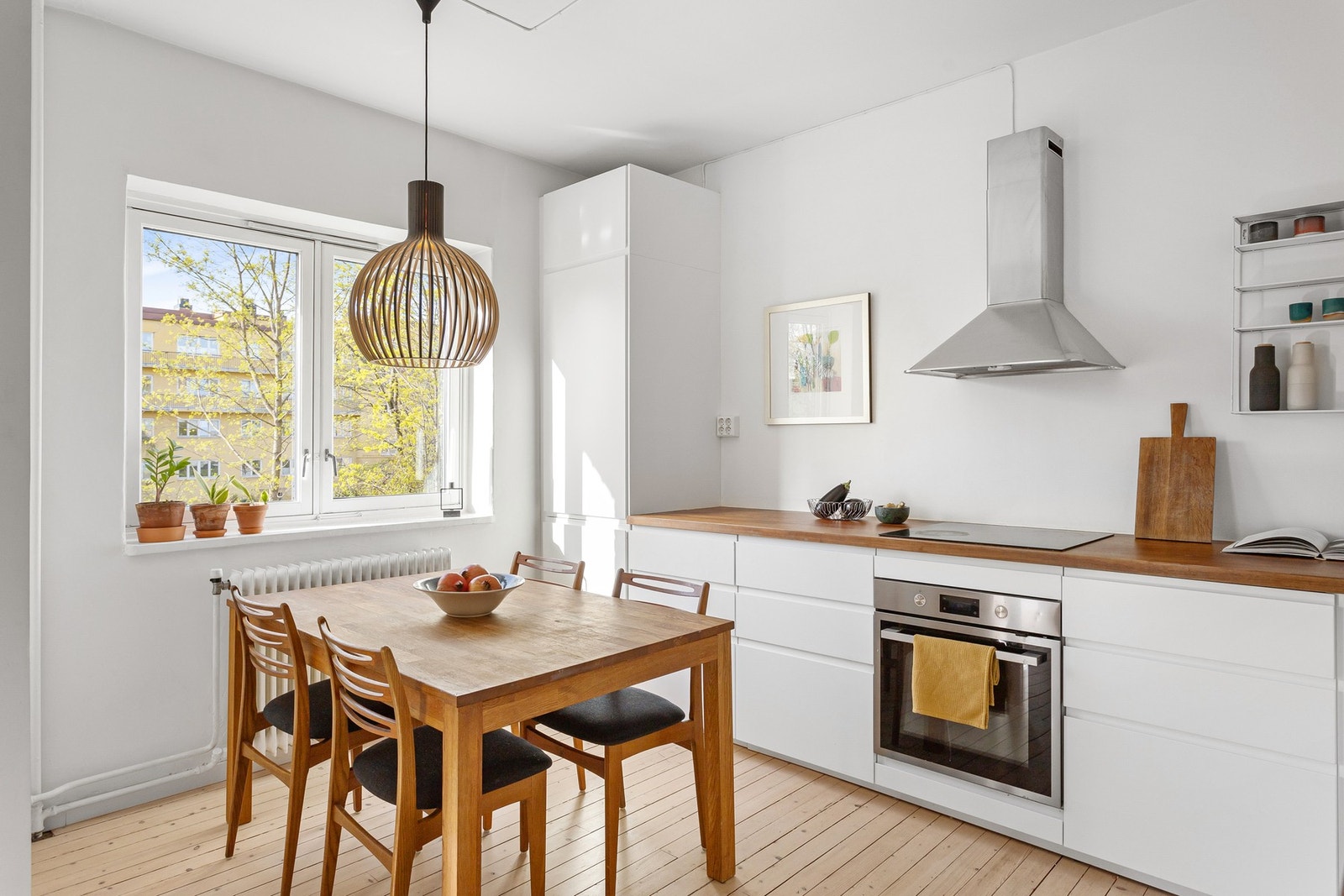 Hvit, stilren innredning med heltre benkeplate og integrerte hvitevarer Galleribilde