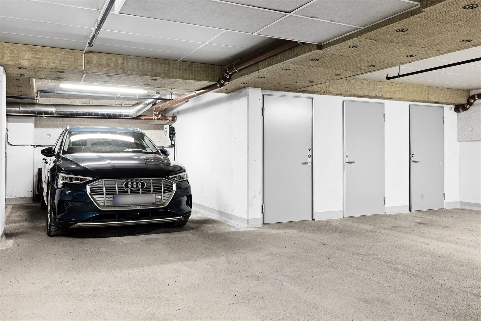 Ekstra stor parkeringsplass i felles garasjeanlegg medfølger - Her er det lader til elbil med hele 11kw ladehastighet - Døren til høyre i bildet er kjellerboden som da ligger praktisk plassert rett ved p-plass Galleribilde