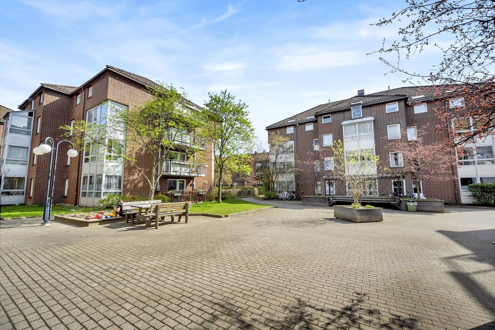 Pent opparbeidet fellesareal med brostein, beplantning og internveier Galleribilde