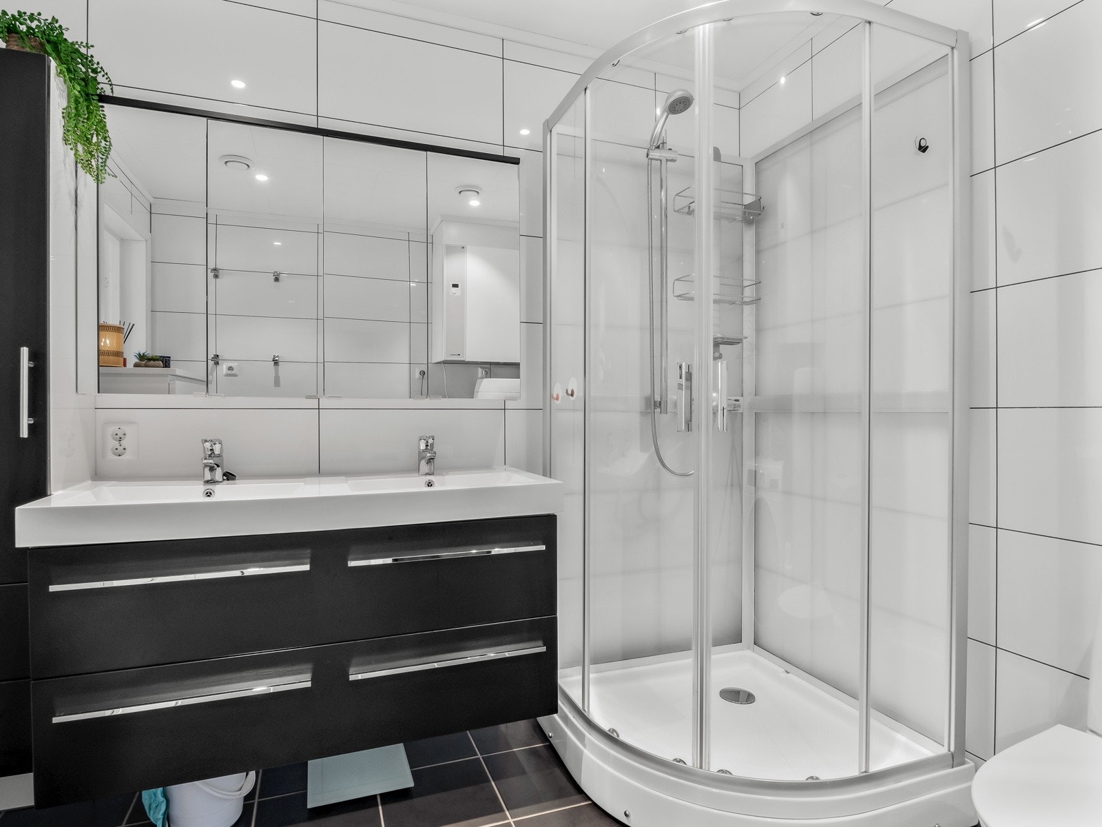 Baderommet har mørk baderomsinnredning mmed oppbevaringsplass og Galleribilde