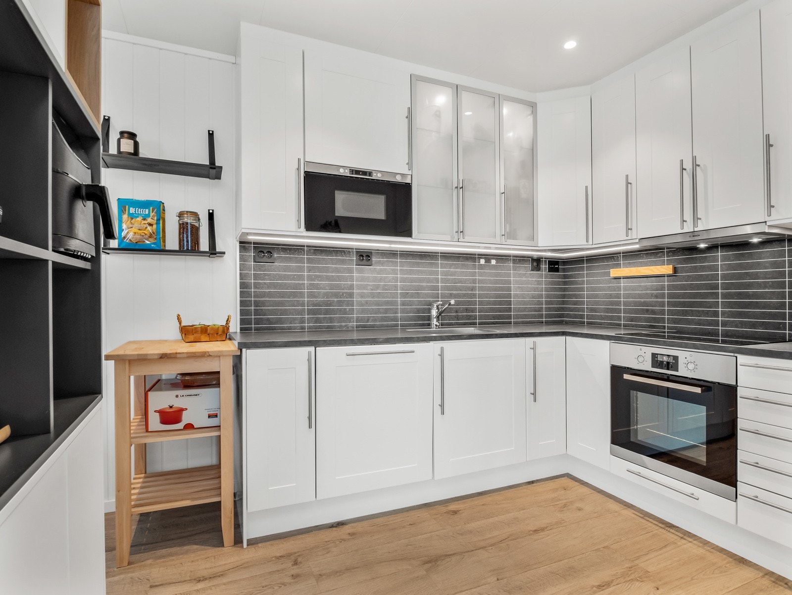 Kjøkkenet har hvite, folierte fronter, og det det Kitchenboard mellom overskap og benkeplate Galleribilde