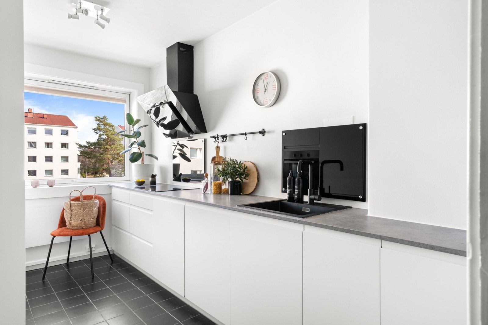 Kjøkkenet er innredet med hvite og glatte fronter med gripekant, og benkeplaten er i lys grå laminat med nedfelt vaskekum. Galleribilde