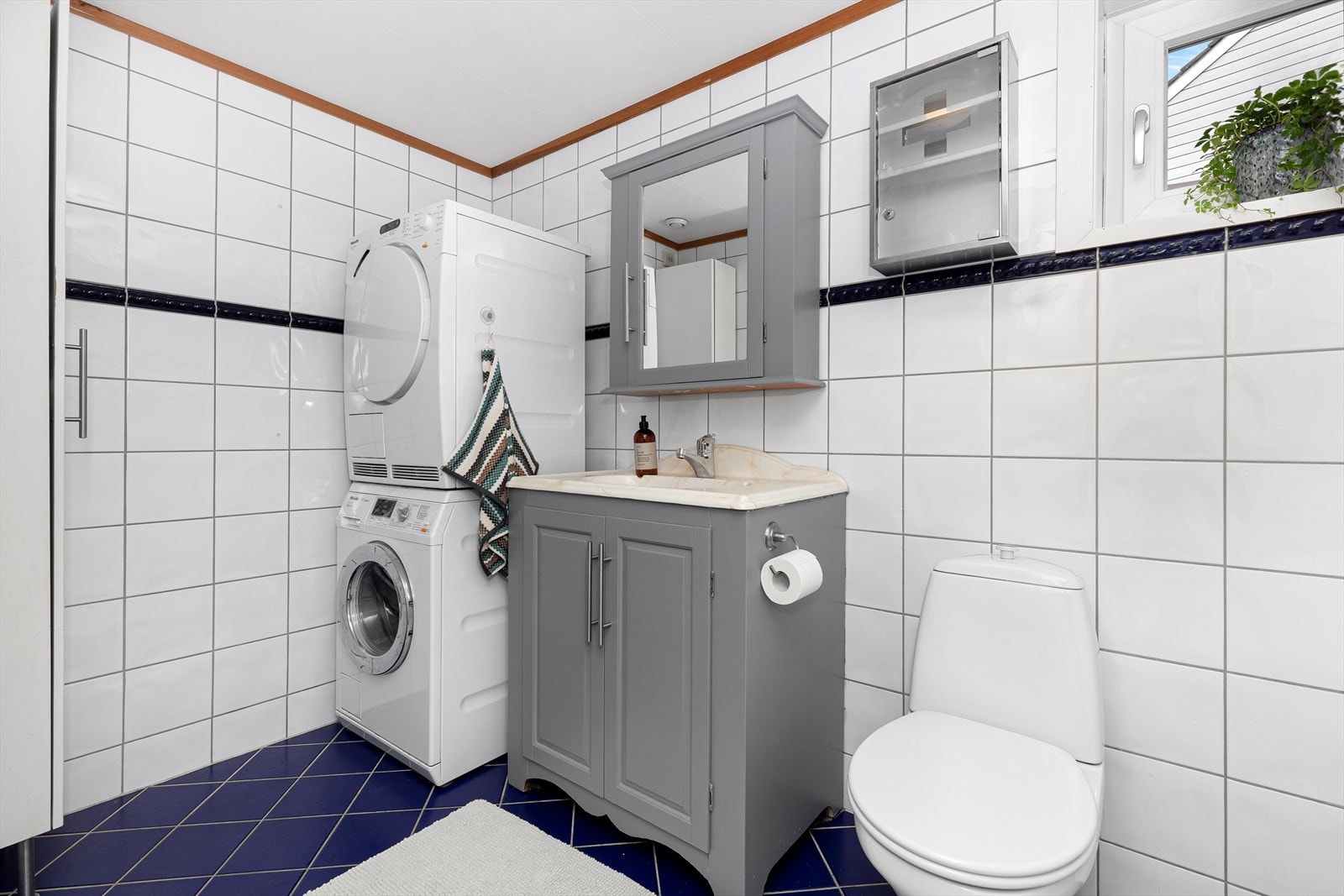 Flislagt baderom med behov for oppussing. Rommet er helfliset, og er innredet med badekar, baderomsinnredning og toalett. Galleribilde