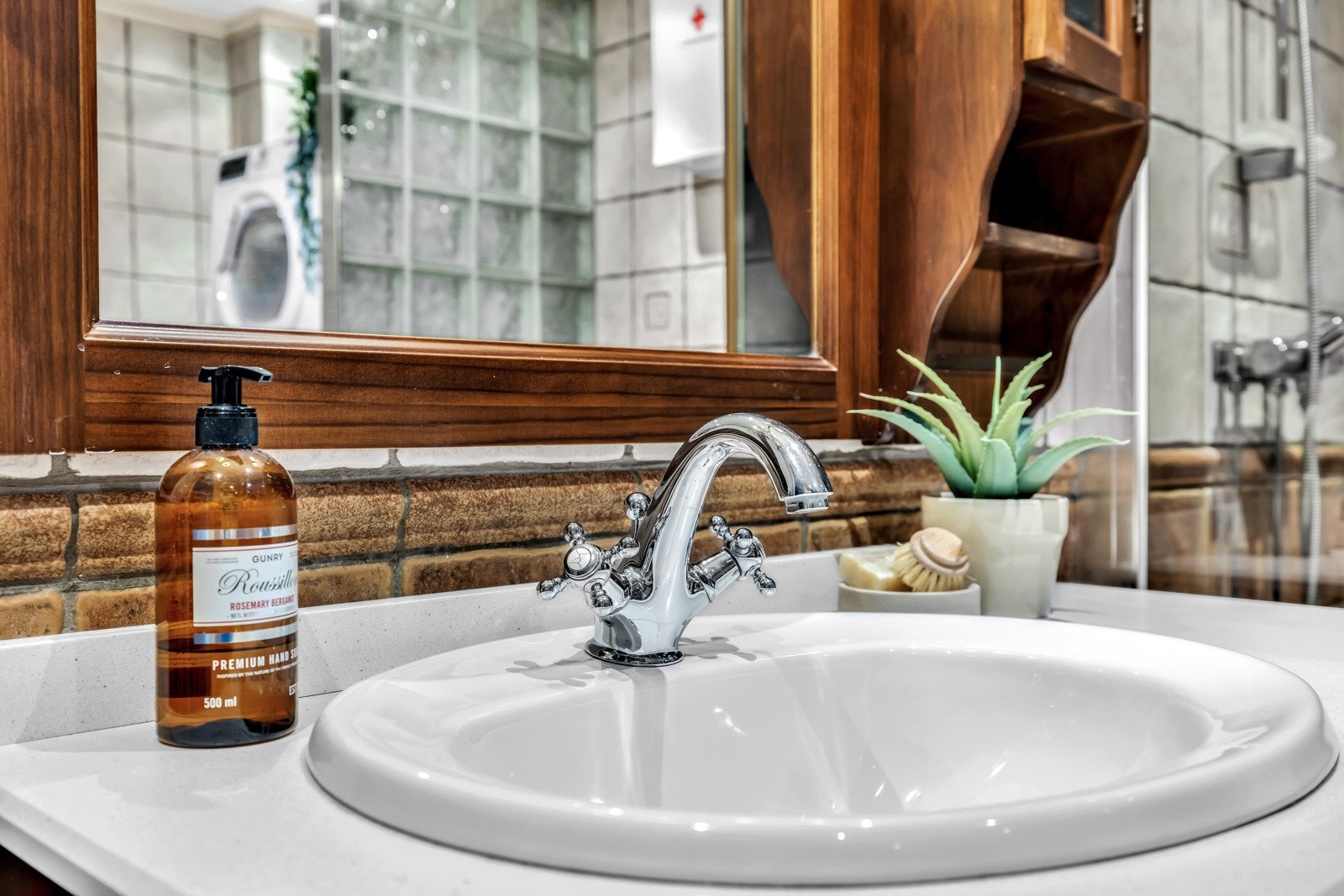 Over servanten henger et vegghengt speil med integrert belysning. En stikkontakt på veggen legger til ekstra bekvemmelighet for bruk av elektriske apparater. Galleribilde