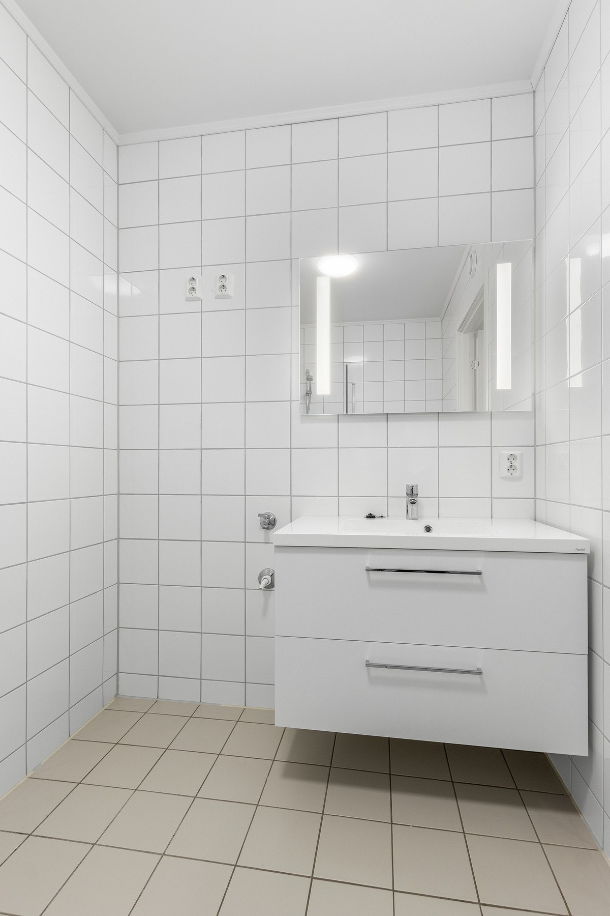 Servant i innredning med lyssatt speil over. Opplegg for vaskemaskin. Galleribilde